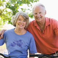 60 to 70 year old couple smile while riding bicycles