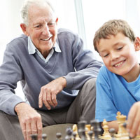 A grandfather plays chess with his grandson